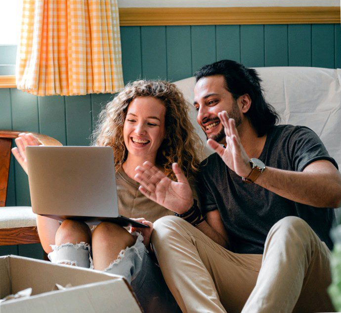 happy couple reducing mortgage payments looking at laptop together